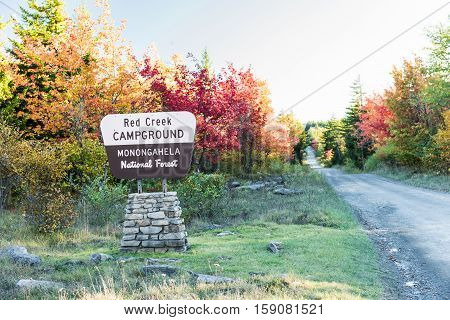 Public sign of Red Creek Campground in Monongahela National Forest with road and autumn trees