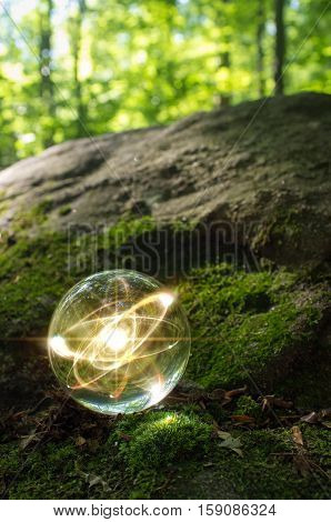 Magic crystal ball atom on forest floor for summer fantasy imagery