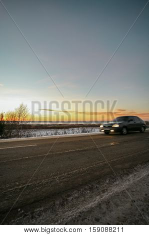 winter road at the snow-covered coast of the lake against the background of a bright decline.