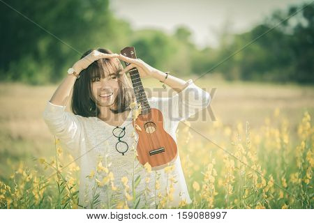 .young Woman Playing On Ukulele On Sunhemp Background