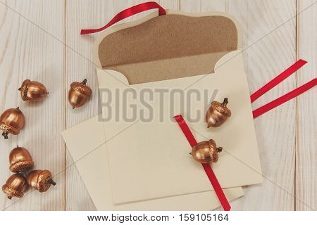 Christmas background.Open envelope with golden acorns.White wooden table.Empty space