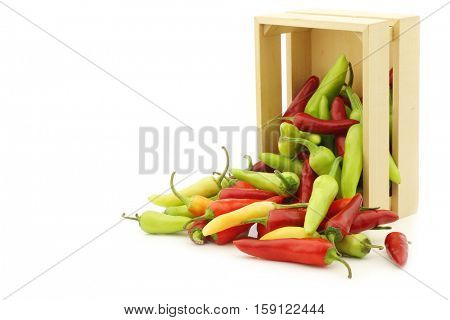 red and green rawit peppers (Capsicum annuum 'Bird's Eye') in a wooden box on a white background