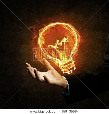 Close of businessman hand holding glowing fire light bulb icon