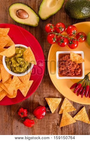 Guacamole and nacho chips on wooden table.