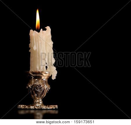 burning old candle vintage bronze candlestick. Isolated On Black Background.