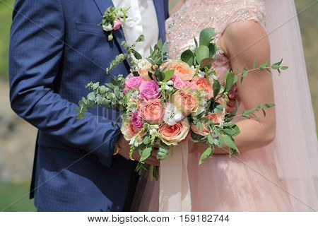 Beautiful bridal bouquet in hands of the bride. Wedding bouquet of peach roses single-head pink rose aqua eucalyptus ruscus gypsophila
