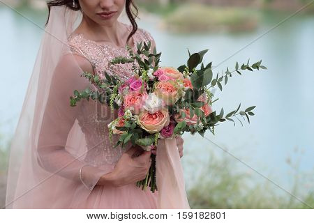 Beautiful bridal bouquet in hands of the bride. Wedding bouquet of peach roses by David Austin single-head pink rose aqua eucalyptus ruscus gypsophila