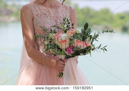 Beautiful bridal bouquet in hands of the bride. Wedding bouquet of peach roses by David Austin single-head pink rose aqua eucalyptus ruscus gypsophila