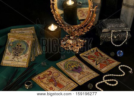 Esoteric still life with the Tarot cards, candle, mirror and crystals. Halloween concept, black magic ritual or spell with occult and mystic symbols, divination rite. Vintage objects on table