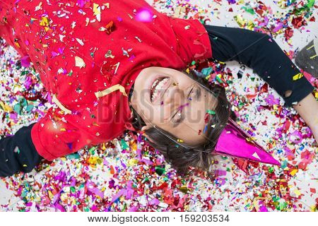 Young boy blows out confetti, isolated on white background