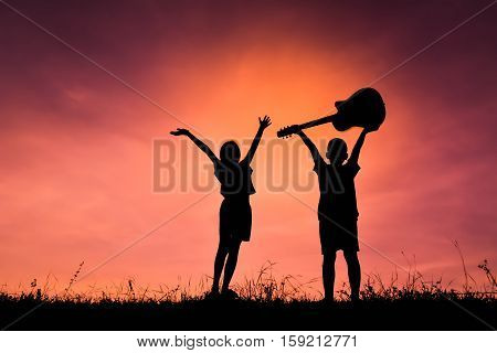 Silhouette of people playing guitar at the sky sunset happy time in holiday vintage tone