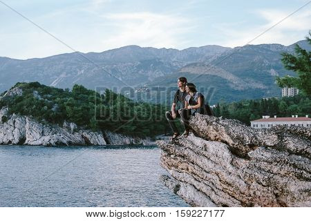 Happy Man And Women Sit Down On A Rock Mountain In Montenegro, Freedom And Travel Cocept