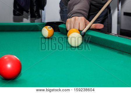 Billiard balls on green table and hand with billiard cue