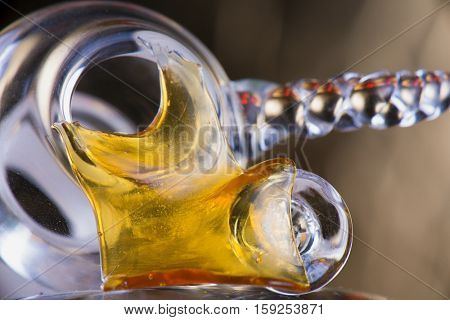 Close up view of a piece of cannabis oil concentrate aka shatter with glass rig bowl and nail 