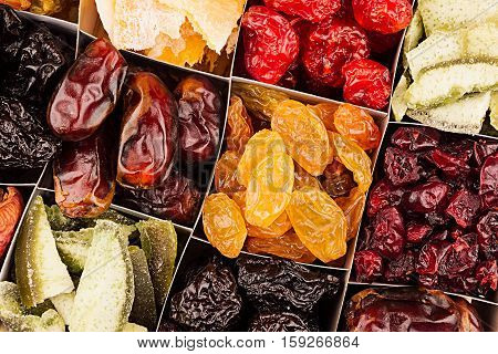 Assortment of dried fruits closeup background in square cells. Decorative pattern of dry exotic fruit. Top view.