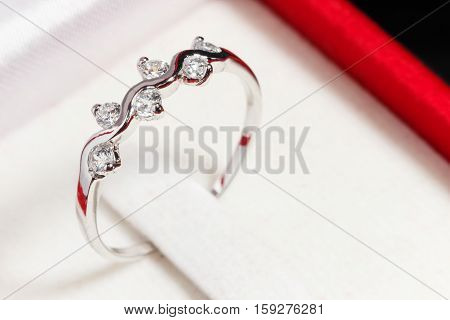 close up silver diamond ring in red ring box