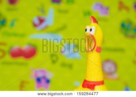 Toy Rubber Shriek Yellow Chicken On Blur Toy Background In Messy Room.