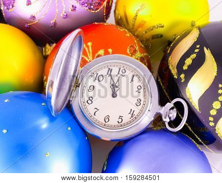 Pocket watch showing almost twelve o'clock (five minutes to the midnight) and multicolored Christmas balls New Year concept