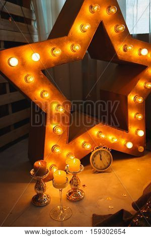 new year clock before midnight with burning candles in sconces and glowing lamps