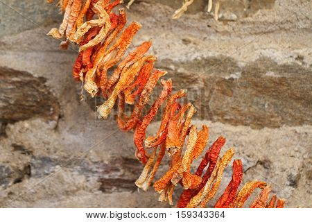 Dried red chili peppers on a stone wall.