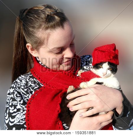 Girl and kitten. Winter day. Red hat and red scarf