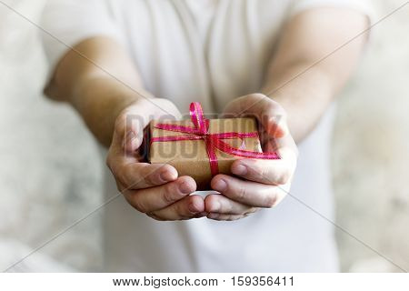 podaroks red ribbon in the men's hands on a white background
