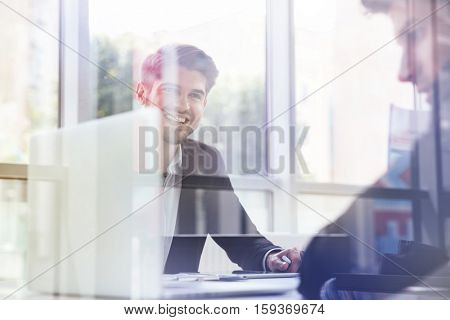 Double exposure of a two cheerful young businessmen with laptop on business meeting in office