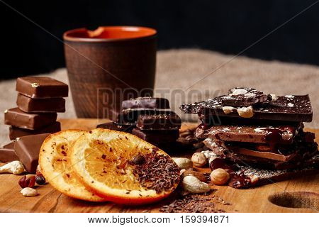 Chocolate candies orange cinnamon and nuts on wooden desk. Copy space.