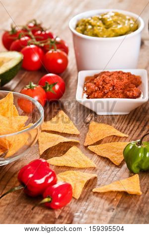 Guacamole and nacho chips on white bowl.