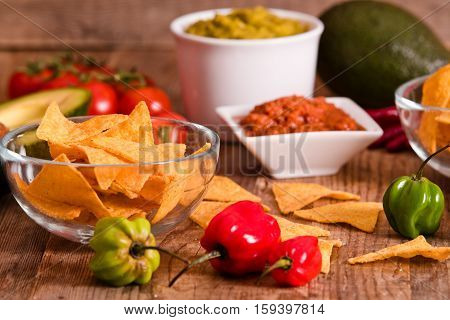 Guacamole and nacho chips on white bowl.