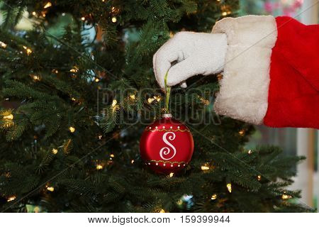 Santa Claus prepares a Christmas Tree with Lights and ornaments for Christmas at a persons house. Santa Loves xmas. x-masTree.   Santa Claus setting.