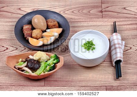 Rice gruel and stewed boiled egg with tofu and streaky pork and fried mixed vegetable served .