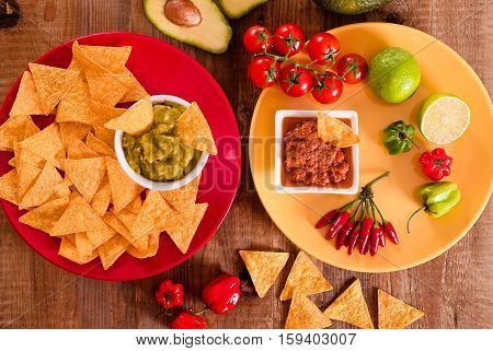 Guacamole and nacho chips on red dish.