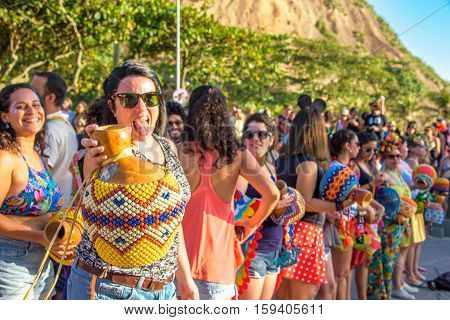 27 November, 2016. Woman in sunglasses with percussion putting out her tongue in the street at sunny day at Festival de Fanfarras Ativistas - HONK RiO 2016 at Leme district, Rio de Janeiro, Brazil