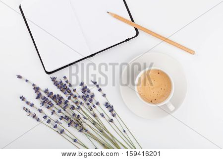 Coffee clean notebook and lavender flower on white table top view. Woman working desk. Cozy breakfast. Mockup. Flat lay style.