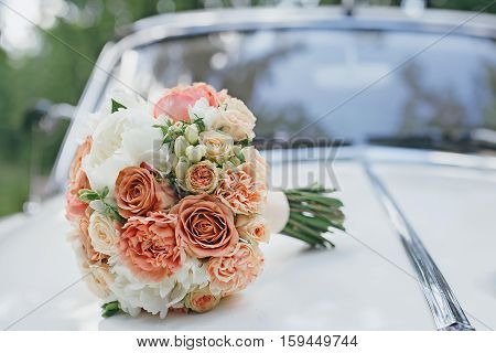 Wedding bouquet on the hood of a white retro car