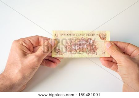 Man Holding Five Bhutanese Ngultrum Banknote In His Hands