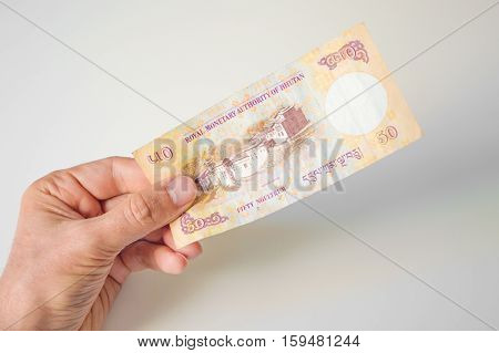 Man Holding Fifty Bhutanese Ngultrum Banknote In His Hand