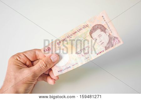 Man Holding Fifty Bhutanese Ngultrum Banknote In His Hand