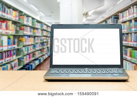 Laptop with blank screen on table with blur bookshelf at libraly Education and technology concept.