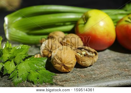 Ingredients for Waldorf salad - celery apples walnuts - fresh and healthy vegetables on granite board.