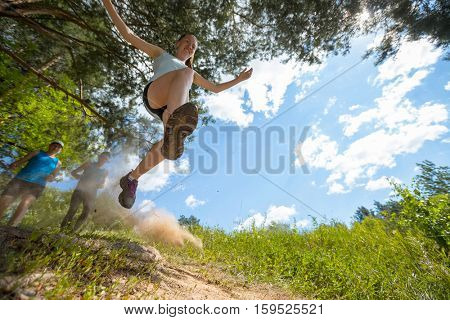 Trail running athlete jumping over camear at sunny day