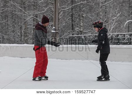 Saint-Petersburg Russia - December 2 2016: Urban outdoor ice rink in the park. Two boys are learning to skate.