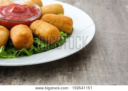 Traditional fried Spanish croquetas (croquettes) with ketchup in plate on wooden background
