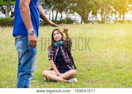 Woman sitting on the grass reaching to shake the hand of man. helping hand and love concept.