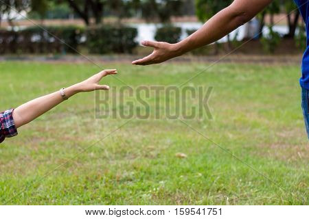 Woman sitting on the grass reaching to shake the hand of man. helping hand and love concept.