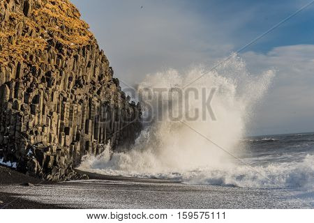 Huge wave crashes with Reynisdrangar, basalt sea stacks situated under the mountain Reynisfjall near the village Vik, Iceland. In February 2016 a Chinese tourist was found dead, perished in the waves.