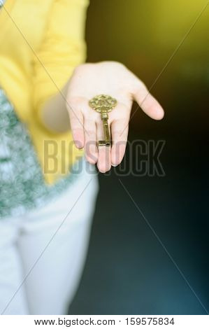 Woman's hands holding a (gold) key in sunny room. Focus on key