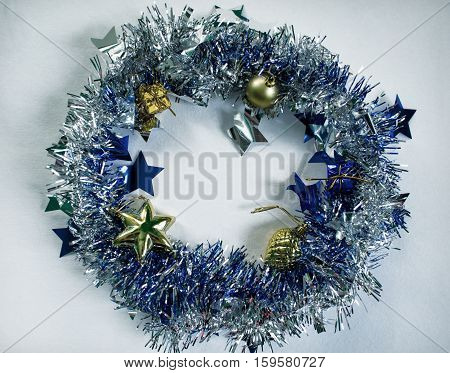 Christmas wreath on white photo. Blue fluffy wreath with gold fir tree toys. Toned photo of Christmas tree decor. Christmas background or template with text place. Christmas decor on white backdrop