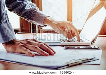 Business man hand using and working with laptop on office desk table close up.Business concept.